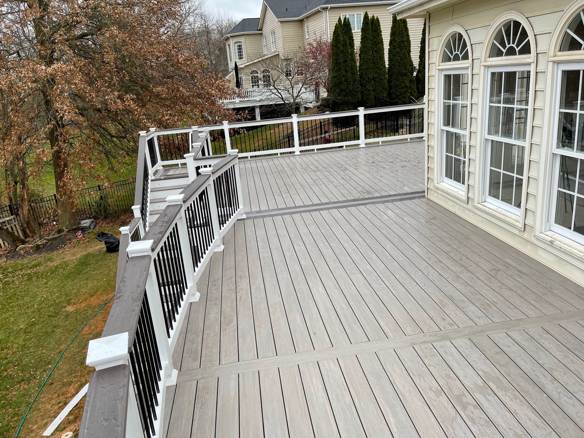 A wooden deck with white railing and windows