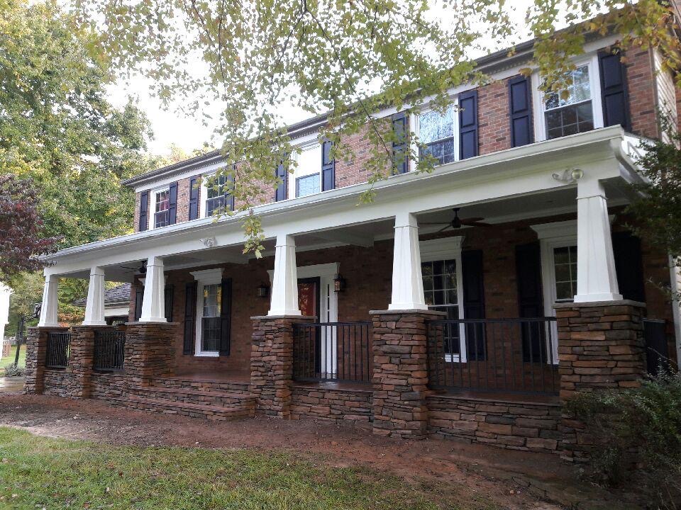 A brick house with white columns and black shutters