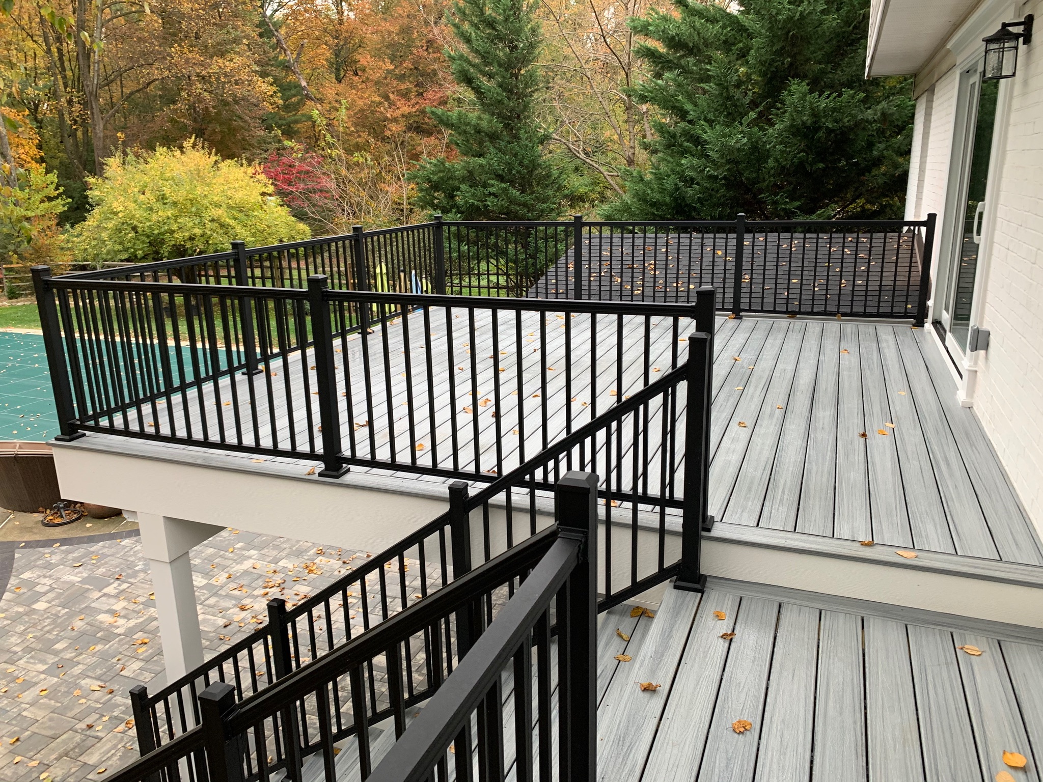 A deck with black railings and a pool in the background