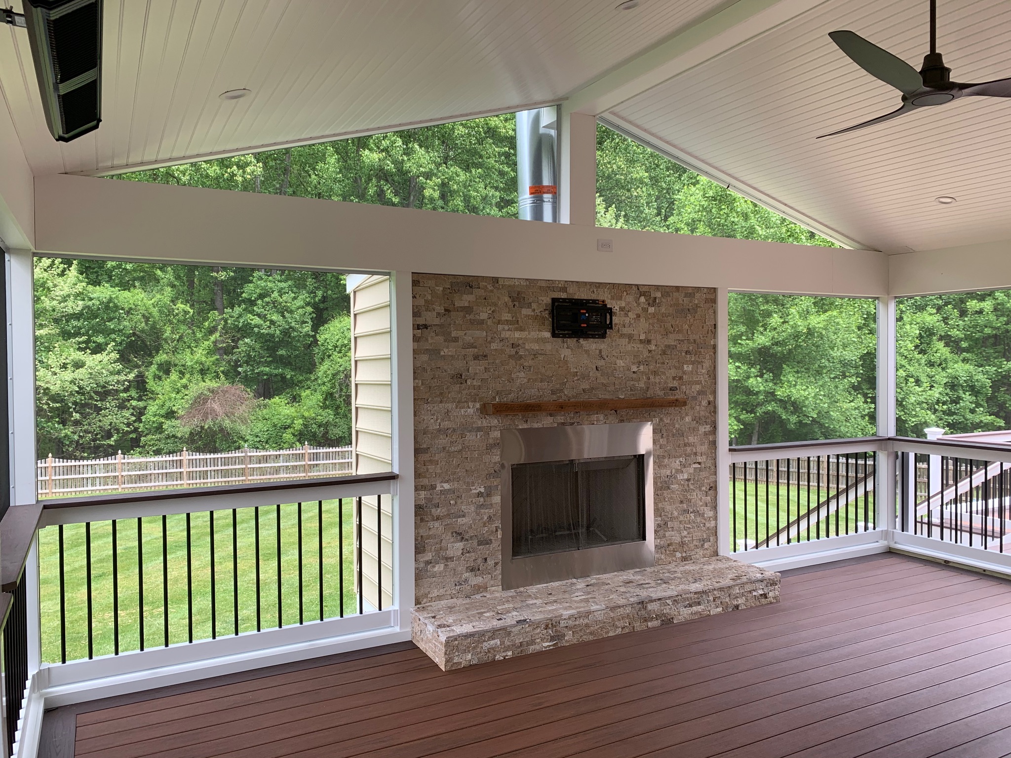 A covered porch with a fireplace and ceiling fan