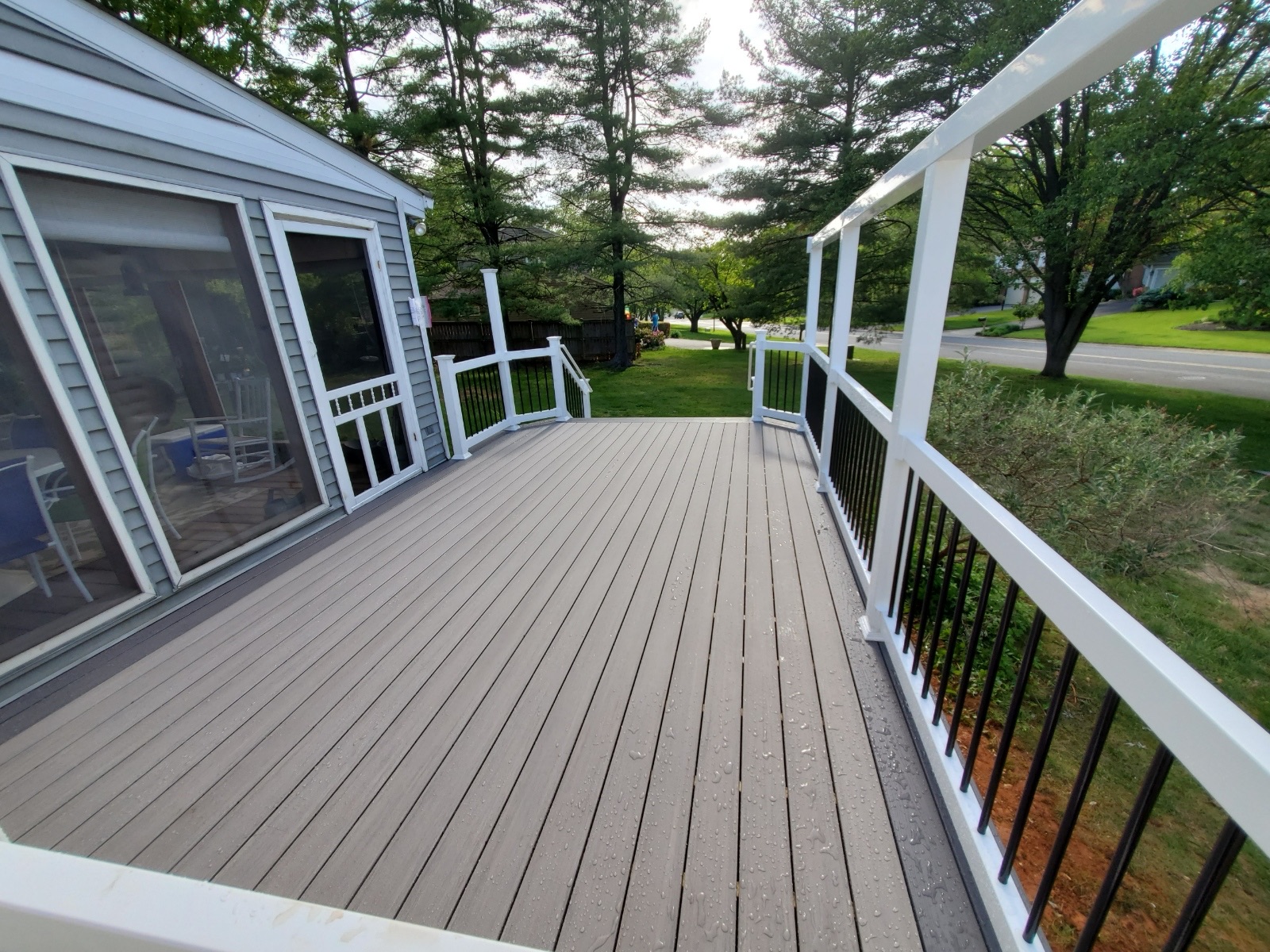 A wooden deck with white railing and windows