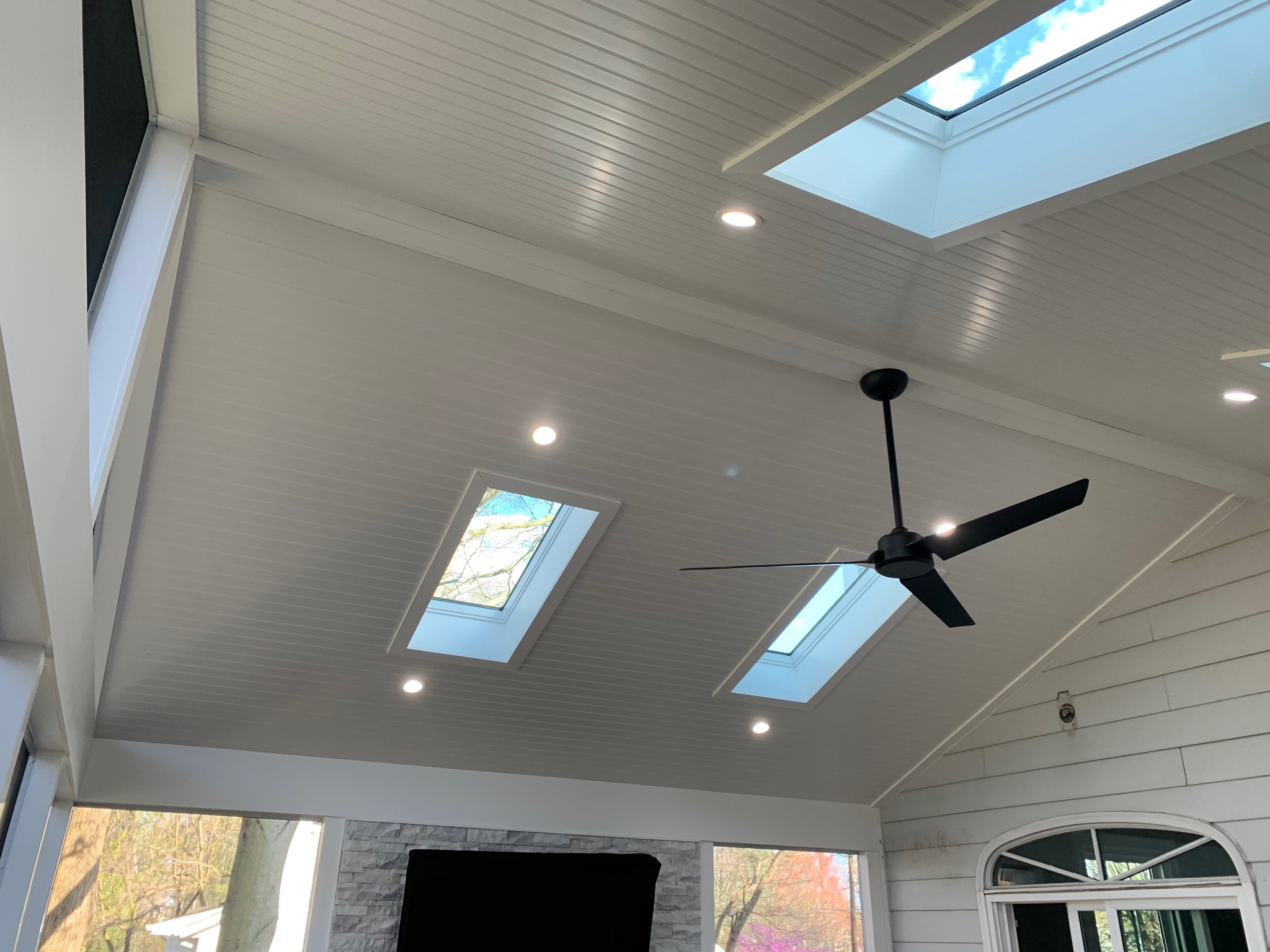 A ceiling fan in a living room with two windows