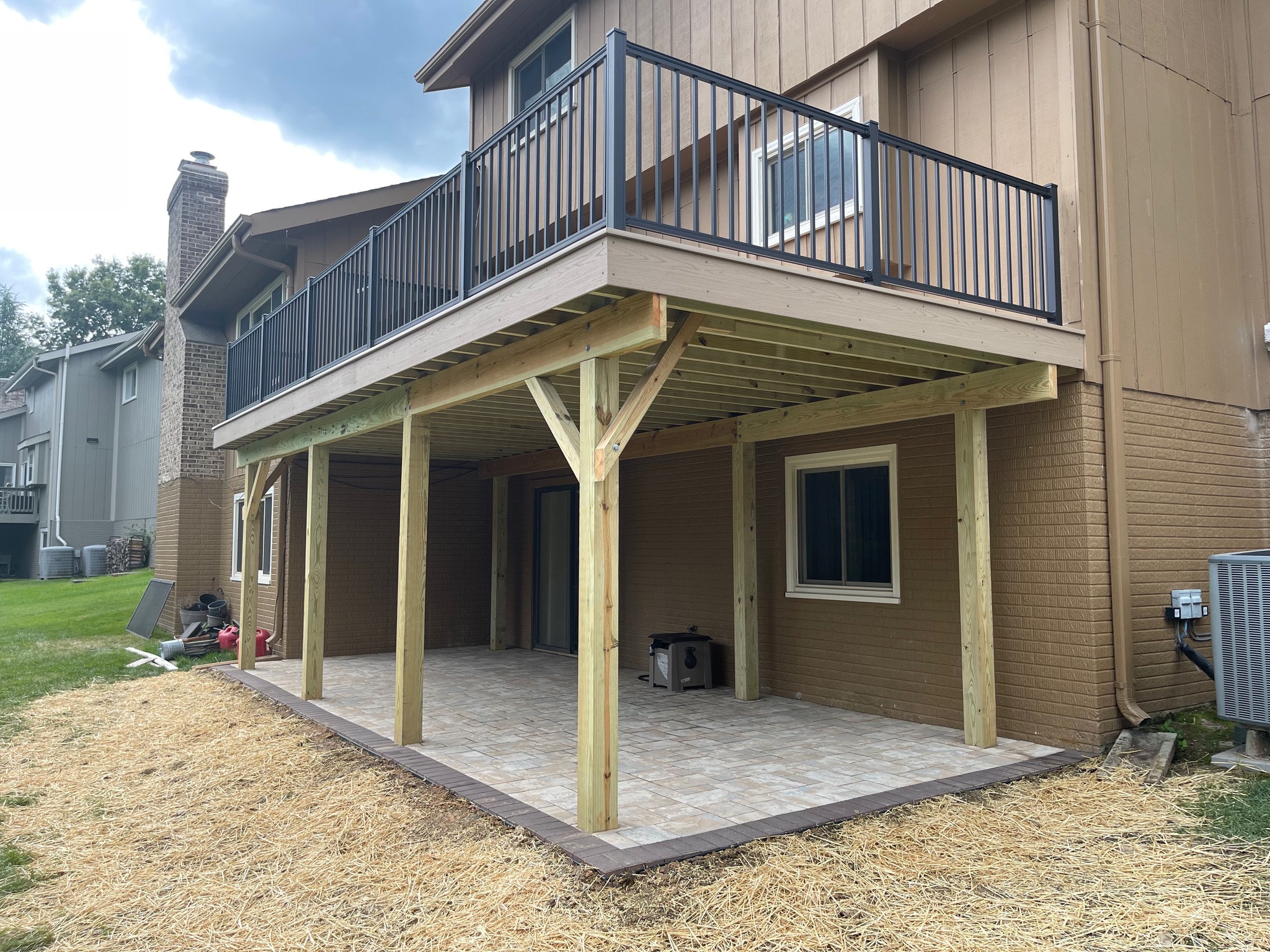 A dog is sitting on a patio under a deck