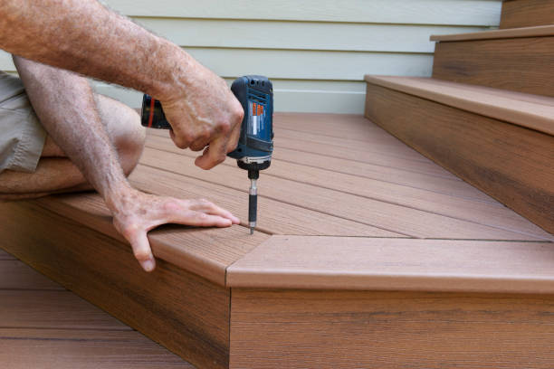 Deck specialist measuring framing connections and stair layout for precise outdoor construction