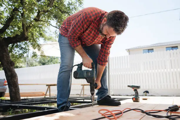 Experienced deck professional inspecting railing connections and structural framing on elevated deck