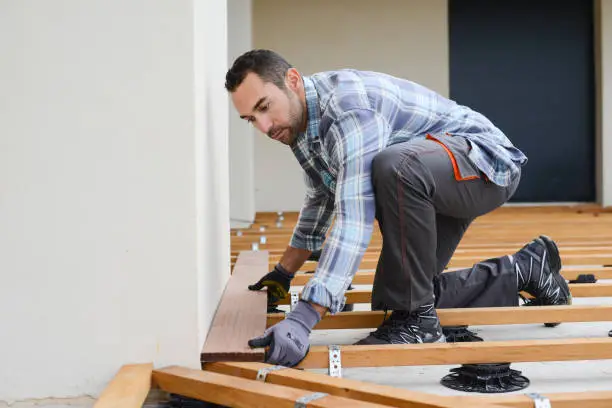 Deck specialist checking framing layout and railing spacing on elevated residential deck