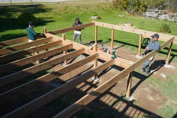 Backyard deck installation underway behind Germantown home with stairs leading to lawn