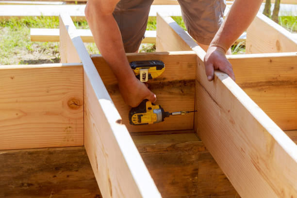 Deck professional inspecting stair framing and railing connections on elevated backyard structure